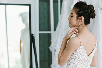 The Asian bride is trying on the wedding dress to dress up to attend the ceremony.