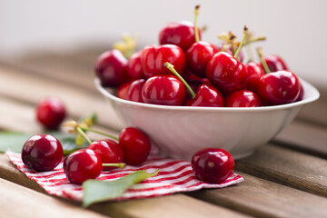 fresh cherries fruits in a white bowl on wooden table