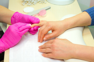 Obraz na płótnie Canvas Close Up shot of a woman in a nail salon. Manicure, washing nail polish. Manicurist remove nail polish remover and a cotton pad.