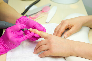 Obraz na płótnie Canvas beautician making hardware manicure. woman hands receiving nail procedure in beauty salon.