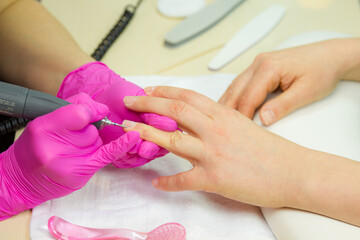 Obraz na płótnie Canvas Beautician making hardware manicure. woman hands receiving nail procedure in beauty salon.