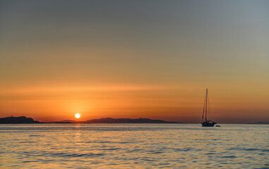 Beautiful sunset on ocean cost of tropical island with single boat in foreground.