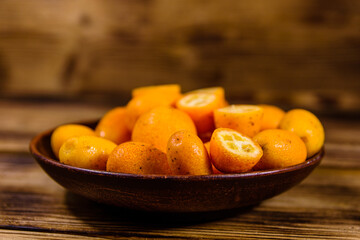Plate with kumquat fruits on wooden table
