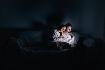 Young cheerful Caucasian couple sitting on the couch in the dark