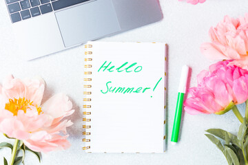 Desk top view. Phrase words Hello Summer. Peonies top view, flat lay. Peony flowers and laptop. Good morning. 