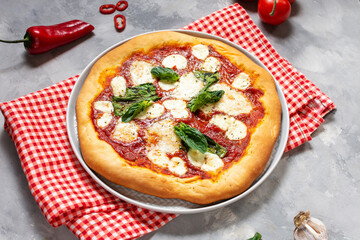Homemade pizza margarita with mozzarella, tomatoes and basil on concrete background