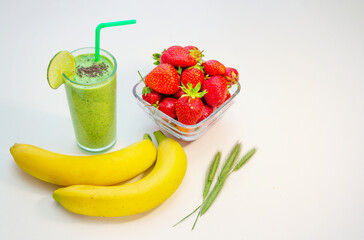 Green smoothie in a glass bananas and ripe strawberries on the table. Healthy breakfast. 