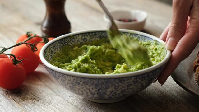 Mashing avocado in bowl with a fork. Preparing vegetarian avocado sauce. Cooking healthy food