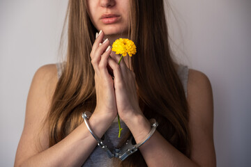 Handcuffed girl with a flower in her hands