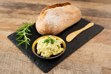 Freshly baked bread and rustic handmade herbs butter on the table.