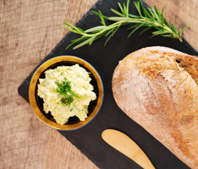 Freshly baked bread and rustic handmade herbs butter on the table.