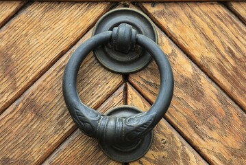 Schwarzer Türklopfer Ring aus Metall auf Holztür