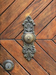 Altertümliches Türschloß mit Türknauf auf einer Holztür mit diagonalen Paneelen
