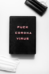 Fuck corona virus, graphic image, black lightbox,rebellion against covid-19 pandemic, resilience against coronavirus crisis concept, black and white mask, flatlay composition, on a white background