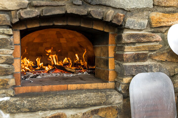 Old stone homemade pizza oven. Fire in the furnace. Homemade baking pizza. Bakery. Traditional Italian food.