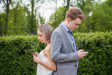 Sad couple using smartphone outdoor