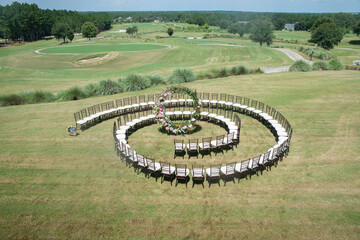 Unique round spiral chair pattern wedding ceremony setting at rolling hills countryside with brown chiavari chairs and white cushions