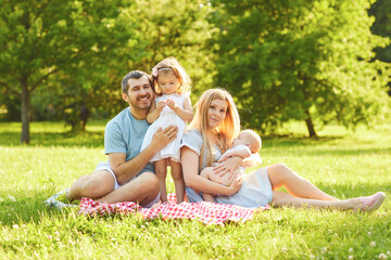 Happy family sitting on the green grass are playing in the park.