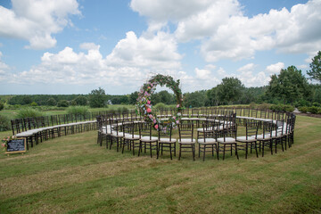 Unique round spiral chair pattern wedding ceremony setting at rolling hills countryside with brown chiavari chairs and white cushions