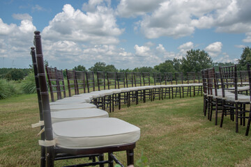 Unique round spiral chair pattern wedding ceremony setting at rolling hills countryside with brown chiavari chairs and white cushions