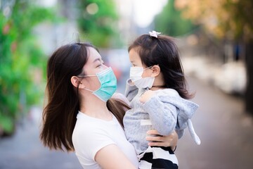 The mother and daughter hugged each other while wearing medical face masks to protect the corona virus and the flu and poisonous dust. Concepts of basic health viewing and prevention. Girl 3 years old