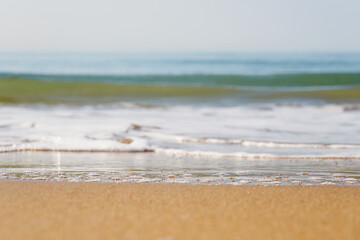 Blurred sea wave with foam on a sandy beach with horizont as a natural background/texture.