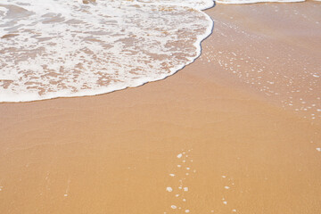 White foam on a sandy beach. Copy space.