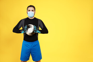 soccer football goalkeeper with a mask on his face with the ball with his hands