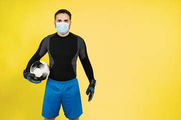 soccer football goalkeeper with a mask on his face with the ball with his hands