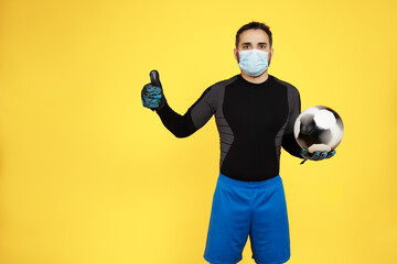 football soccer goalkeeper with a mask on his face waving with his finger doing ok and a ball in his hands