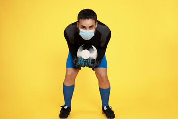 football soccer goalkeeper wearing a mask stopping the ball with his hands