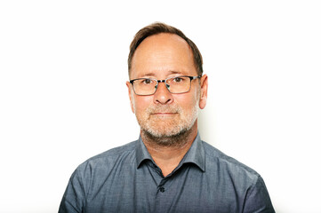 Close up portrait of middle age man taken on white background, wearing grey shirt and glasses