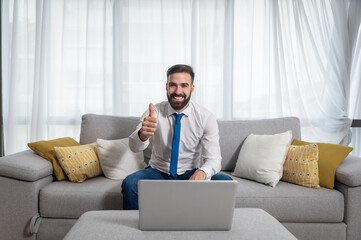 Young freelancer business man working at home showing thumb up  online conference meeting through the laptop computer to his boss and other colleagues as manager after preparing to present new project