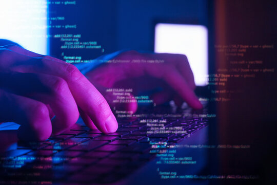 programmer or hacker coding on laptop in dark room, cyber security concept