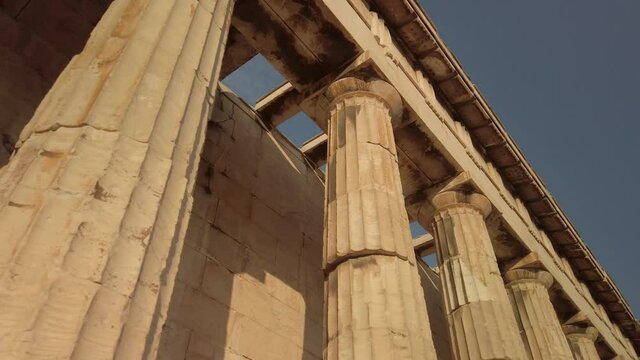 Walking below the Temple of Hephaestus in ancient agora of Athens, Monastiraki district, Greece. The most well-preserved ancient Greek temple. POV from the base of the temple. Lifestyle of ancient GR