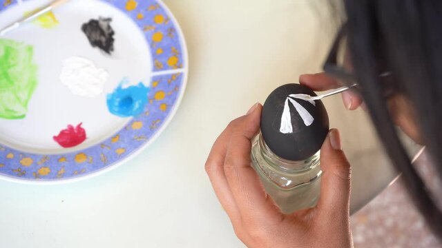 Close up of a caucasian woman starting to paint details on a ester egg