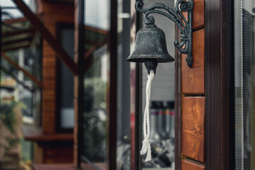 An old bell at the entrance. Ringing bell to call. Bell as a decorative ornament
