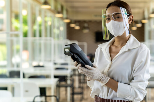 Waitress with face mask hold credit card reader.