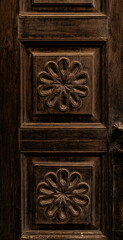 Entrance door of an Italian house from the late 1800s. Doors made of solid dark wood, with large geometric floral motifs carved and inscribed in relief squares. Wood needs restoration. Italy.