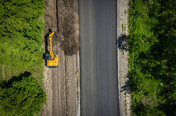 Road repairs. Excavator bucket removes soil along the roadbed