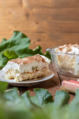 selbstgemachtes Tiramisu mit Rhabarber, Creme, Sahne, Zimt, Löffelbiscuit und Mascarpone auf einem Tisch aus Holz