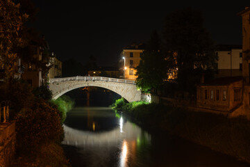 Fototapeta na wymiar Night view of Ponte San Michele (San Michele Bridge) in Vicenza. This single-span bridge made of stone and marble is inspired by the bridges of Venice. The water of the Retrone river flows calmly.
