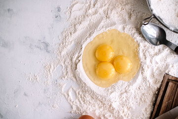 Chicken eggs in flour on the kitchen table, ingredients. Preparation for baking, culinary recipes. Flat lay and copy space.