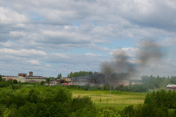 The fire in the warehouse. Thick black smoke is coming from the warehouse.