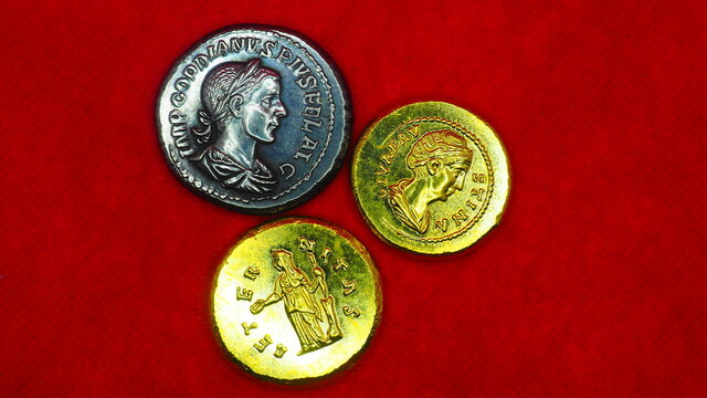 Silver and gold roman coins on red background
