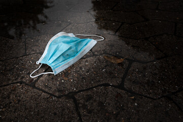 Corona is over! Really...? Gebrauchte schmutzige Atemschutzmasken liegen achtlos weggeworfen auf nasser Straße