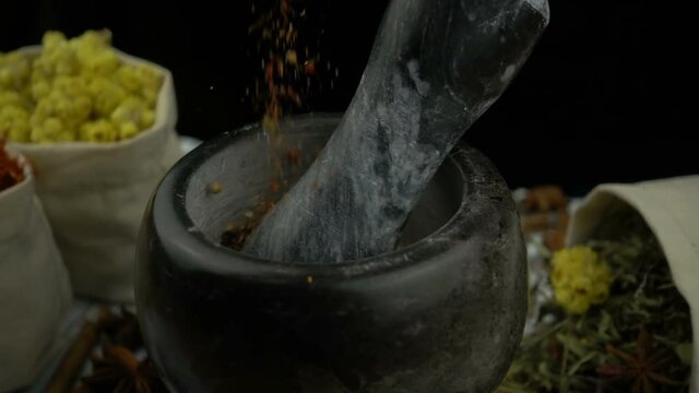 Red pepper falling into the granite mortar with pestle in slow motion. Healthy and organic food, herb medicine, natural care, aromatherapy and organic cosmetics concept.