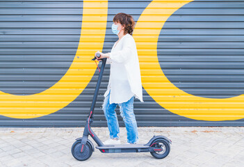 New normal. Woman girl with a mask using an electric scooter. Woman using electric and ecological transport Safety and pandemic concept. Coronavirus. Social distance. Human life in Social distance