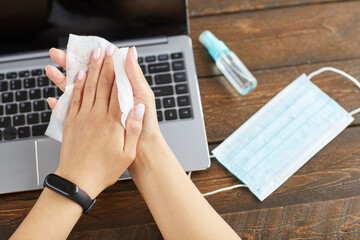 Top view close up of unrecognizable young woman sanitizing hands with cleaning wipes while working at home office in quarantine, copy space