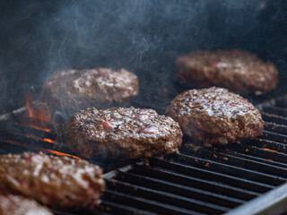burgers cooking on an open flame grill top